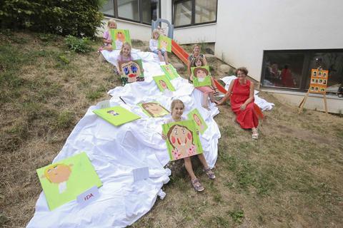 Stolz präsentiert ein Teil der Kinder die Werke. Rechts zu sehen sind die Projektleiterinnen Kirsten Osadschy (rotes Kleid) und Nadine Ehrhardt. Foto: pakalski-press/Andreas Stumpf