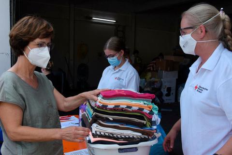Limburg-Weilburg hilft: Claudia Streng gibt vier Körbe voller Kleidung an Haide Leuninger vom DRK.   Foto: Margit Bach 