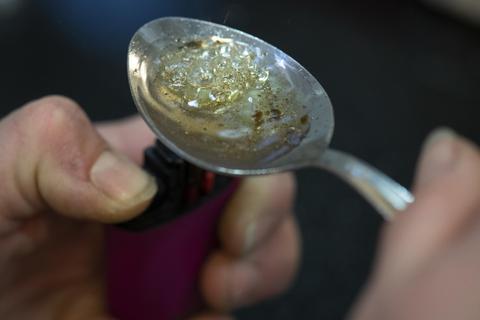Über der Flamme eines Feuerzeuges kocht eine drogensüchtige Frau in einem Druckraum im Bahnhofsviertel eine Portion Crack in einem Löffel auf, um sich die Droge anschliessend zu spritzen. Süchtige können hier unter kontrollierten Bedingungen mitgebrachte Drogen konsumieren. Foto: dpa