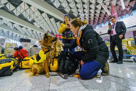 Rettungshund "Ellis" von der Hilfsorganisation "@fire" sitzt mit seiner Hundeführerin in der Abflughalle des Frankfurter Flughafens. Nach einem verheerenden Erdbeben in der Türkei und Syrien wird mit vielen Todesopfer gerechnet. Rettungskräfte aus Deutschland, unter anderem die Hilfsorganisation "@fire", machen sich auf den Weg.