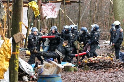 Polizisten tragen drei Aktivisten, die ihre Arme in Metallrohre gesteckt und sich so miteinander verbunden haben, aus dem letzten verbliebenen Camp im Dannenröder Forst.  Foto: Nadine Weigel/dpa