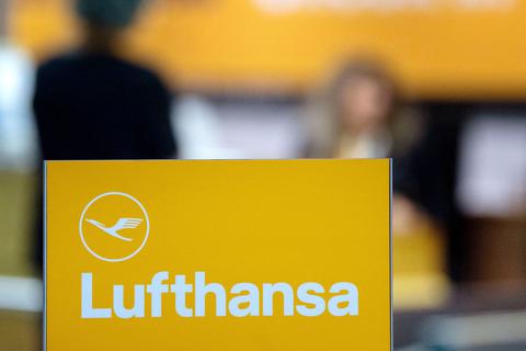 Das Logo der Lufthansa ist auf einem Ständer vor einem Schalter der Fluggesellschaft in einem Terminal eines Flughafens zu sehen. Foto: dpa