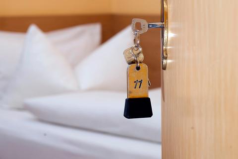 Ein Schlüssel mit der Nummer 11 im Schloss einer geöffneten Hotelzimmer-Tür