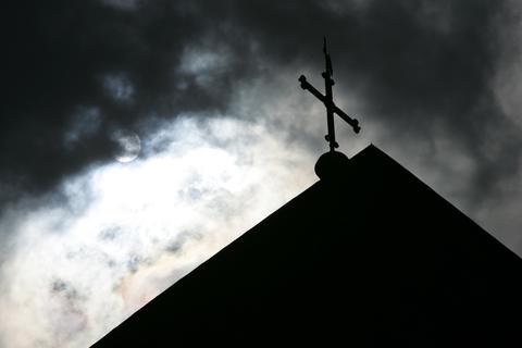 Ein Kreuz auf einem Kirchendach. Foto: dpa