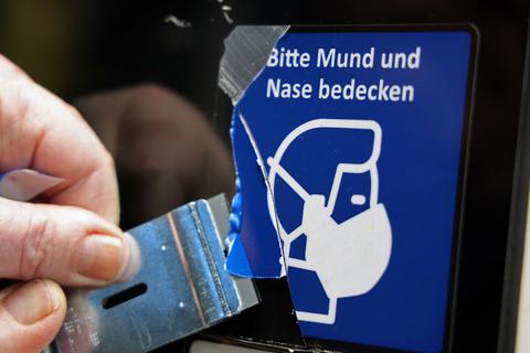 An einer Straßenbahn-Tür wird ein Piktogramm mit dem Hinweis auf die Maskenpflicht entfernt. Auch in Worms muss im öffentlichen Nahverkehr kein Mund-Nasenschutz mehr getragen werden.
