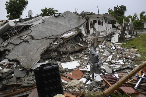 Ein Mann geht über die Trümmer eines eingestürzten Hauses, nachdem der Tropensturm «Grace» über das Gebiet hinweggefegt ist. Nach dem Erdbeben in Haiti mit mehr als 1400 Toten haben starke Regenfälle die Menschen in der betroffenen Region im Südwesten des Karibikstaates in neue Nöte gestürzt.  Foto: Matias Delacroix/AP/dpa 