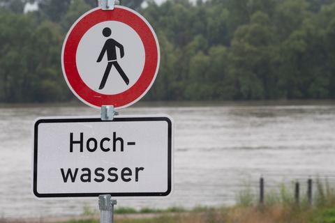 Ein Schild weist auf Hochwasser am Rhein hin.  Foto: dpa