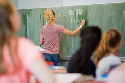 Eine Lehrerin schreibt im Unterricht etwas an die Tafel. Symbolfoto: dpa