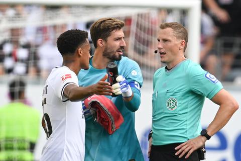 Eintracht Frankfurts Tuta (li.) und Torwart Kevin Trapp (Mitte) diskutieren nach dem Spiel mit Schiedsrichter Martin Petersen.  Foto: dpa/ Arne Dedert
